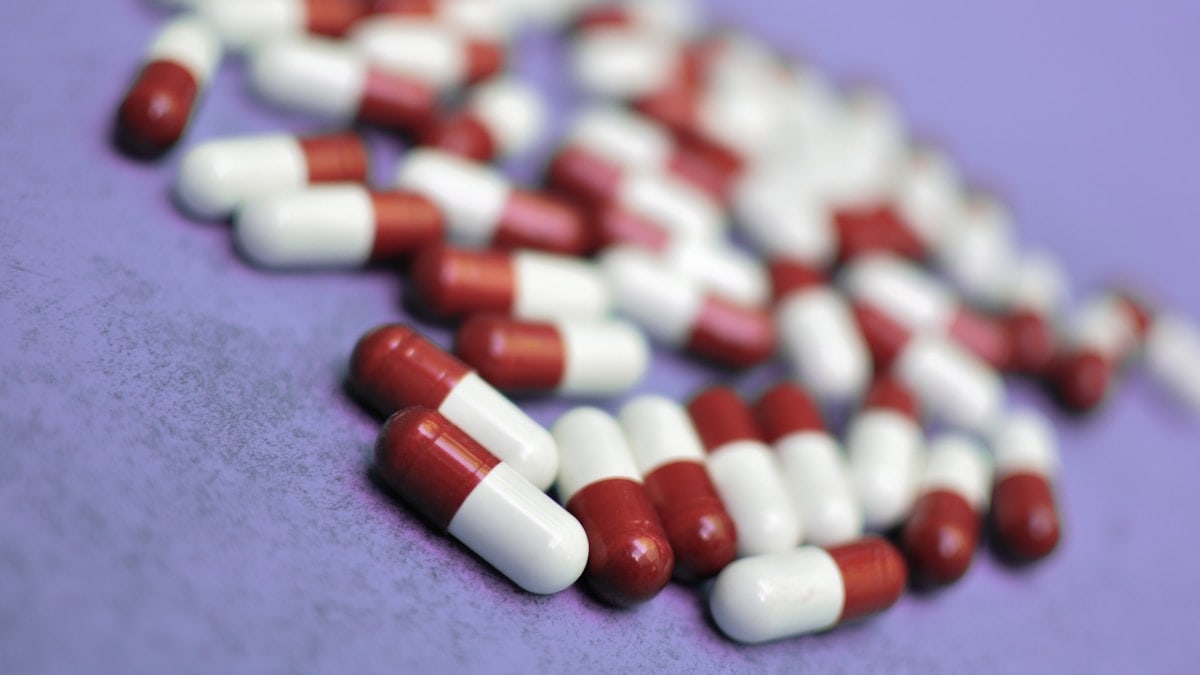 Pills are scattered on a purple surface.